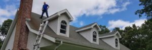 man stands on roof of home Seamless Experts residential and commercial exterior remodeling Ozarks Missouri